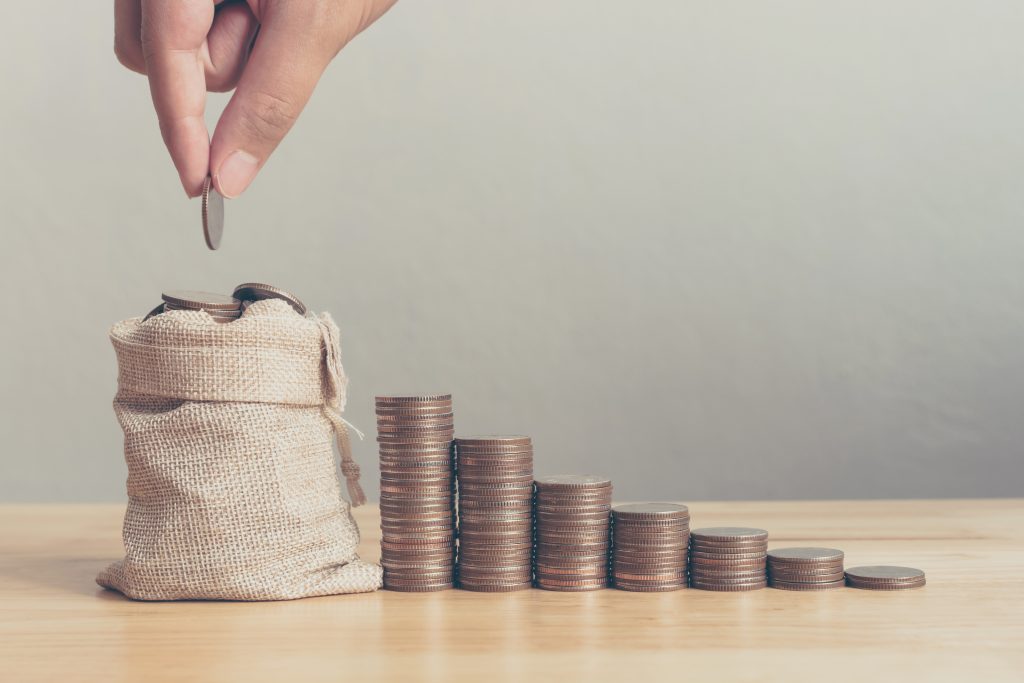 Hand of male or female putting coins in money bag with coin stack step growing growth saving money, Concept finance business investment