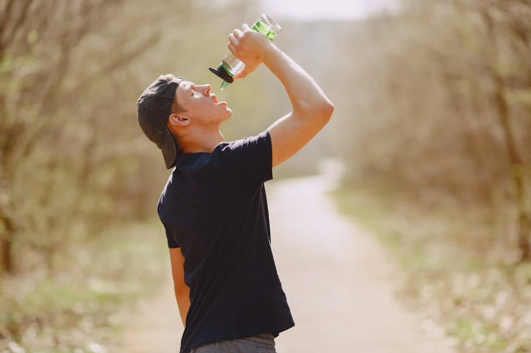a man standing on a trail drinking from a water bottle